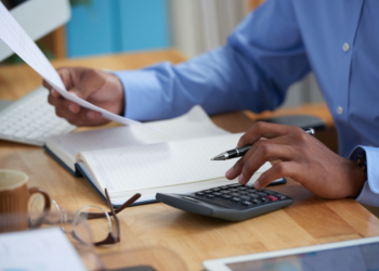 Imagem de um homem fazendo contas em uma calculadora